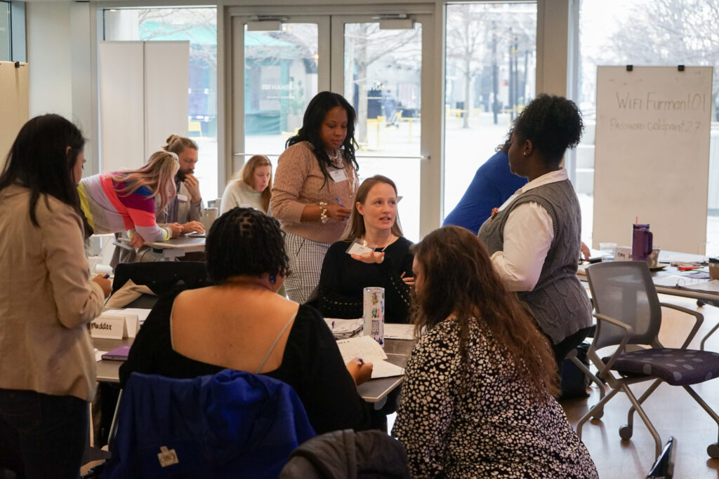 a group of diverse women are discussing and interacting around a table